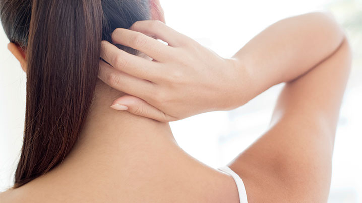 woman touching back of her neck